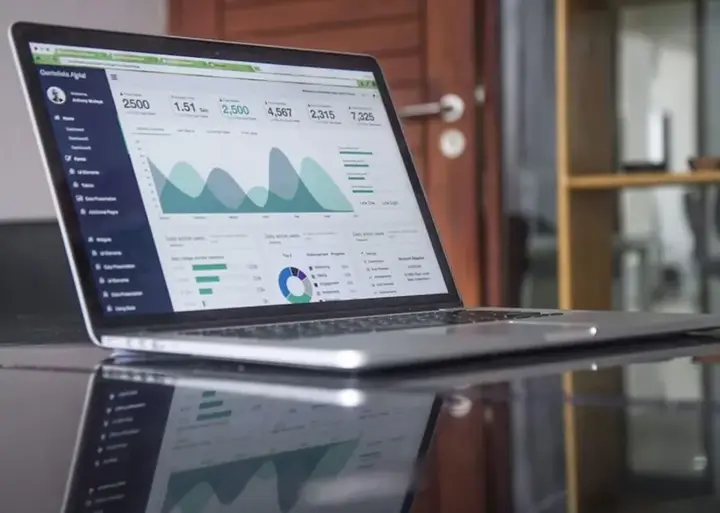 Portátil mostrando un dashboard de analíticas con gráficos y KPIs en verde